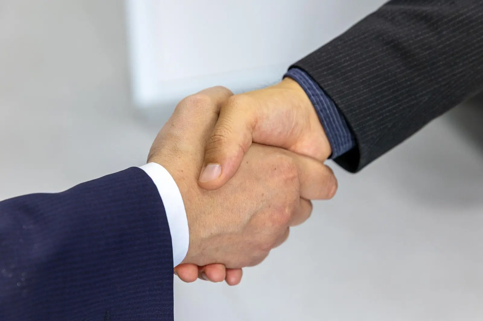 Poignée de main entre deux dirigeants à l'issue d'une négociation de cession d'entreprise.